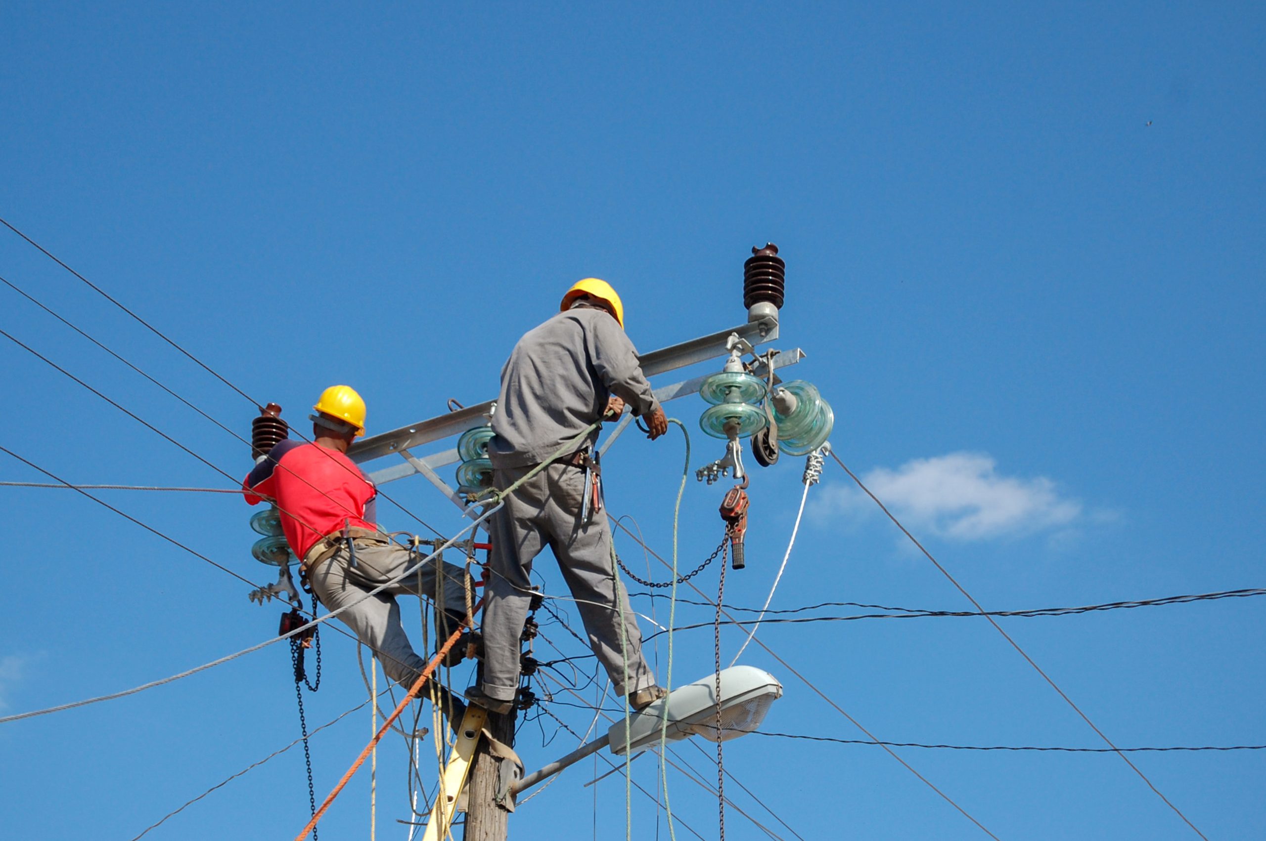 low angle shot electric linemen working pole scaled